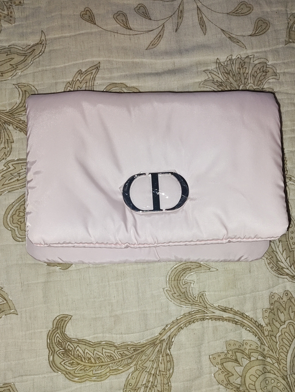 soft pink Dior beauty pouch features a distinct CD monogram plaque on the front.